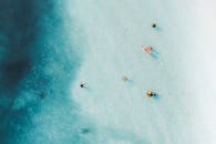 航拍照片捕捉到人们在清澈的蓝色水中享受和放松，周围环绕着大自然的美丽