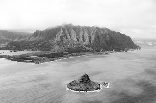 Grayscale Photo of Rocky Mountains near the Sea