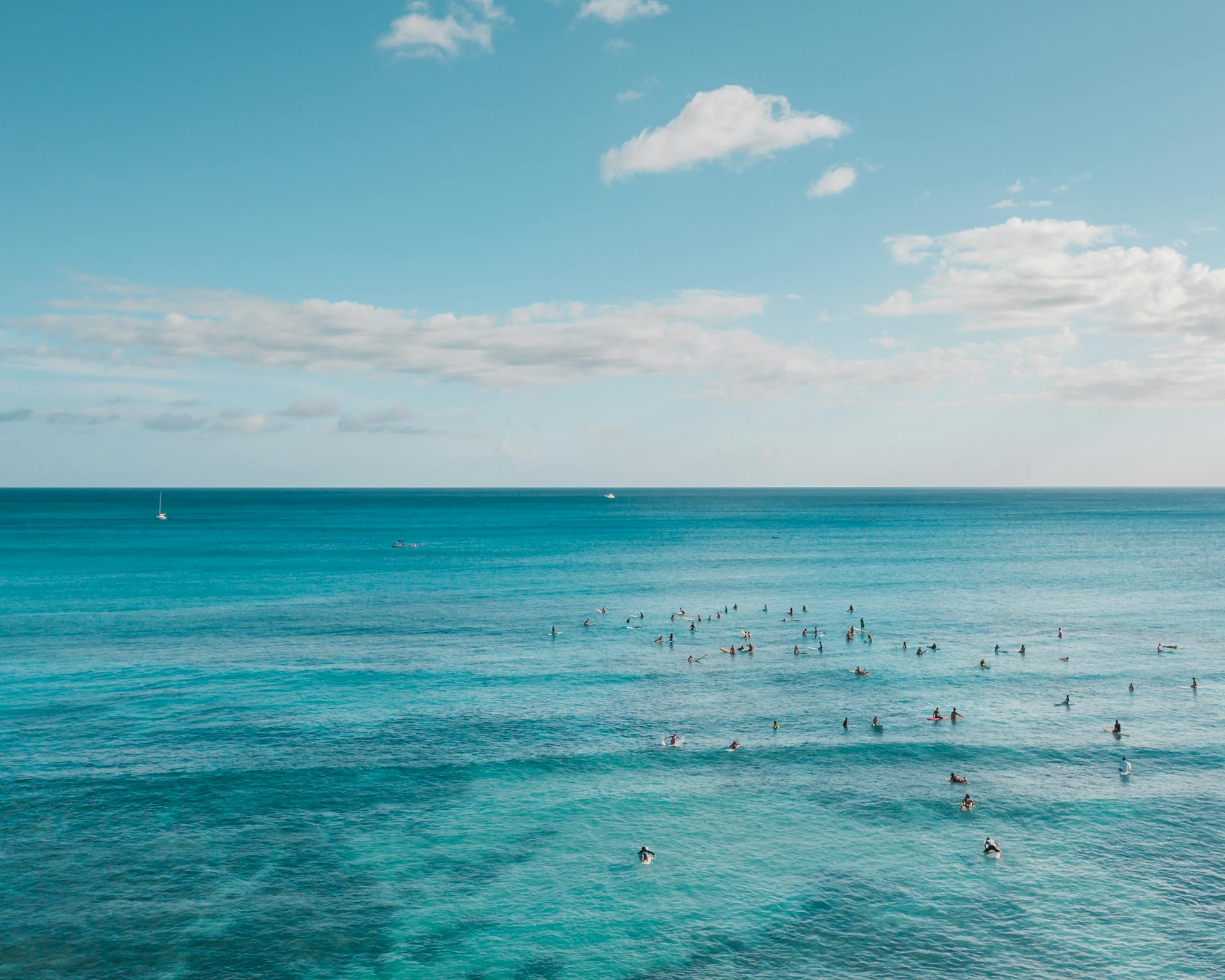 A scenic aerial shot capturing people swimming in a beautiful, clear blue ocean.