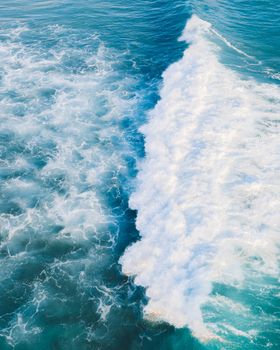 从高角度俯瞰海浪，绿松石海面上泛起白色泡沫，捕捉了运动与自然之美