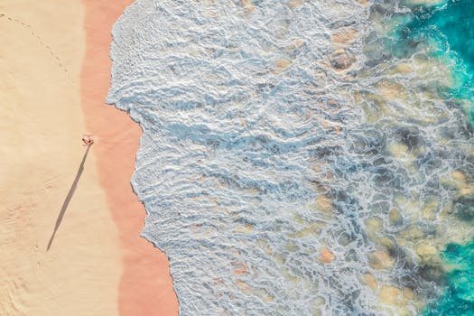 令人惊叹的航拍照片中，海浪拍打着沙滩，沙滩上躺着一位孤独的日光浴者