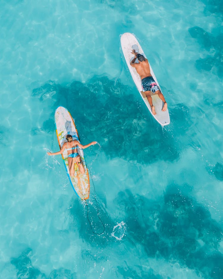 Surf Boarders Floating On Turquoise Seawater