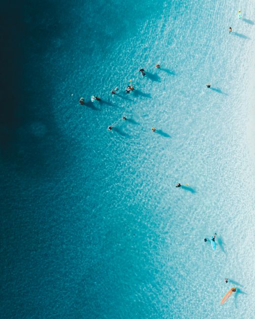 A stunning aerial shot showcasing surfers enjoying the turquoise ocean waters, perfect for summer recreation.