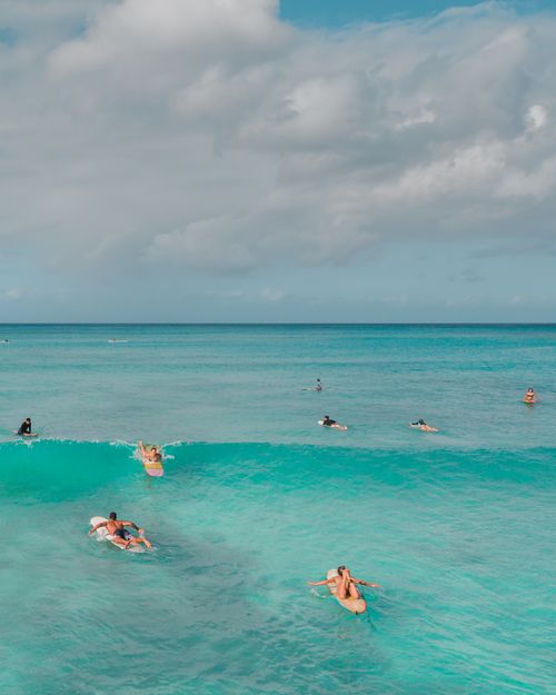 Free A group of surfers enjoy turquoise waves under a sunny sky, capturing a sense of freedom and adventure. Stock Photo