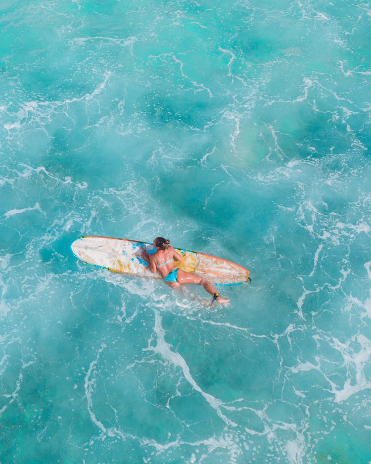 Woman Climbing On Top Of The Surfboard 