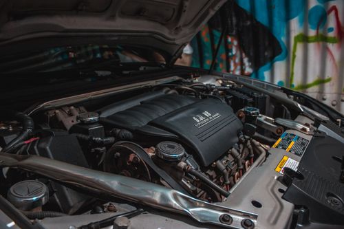 Free Internal combustion engine and other components of mechanism of expensive luxury sports car parked next to wall decorated with graffiti Stock Photo