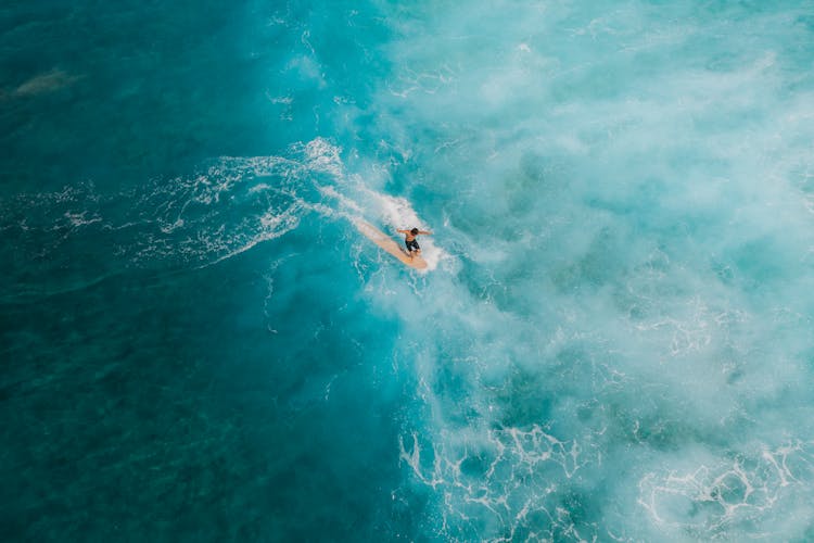 Man Surfing On Beautiful Blue Sea Water