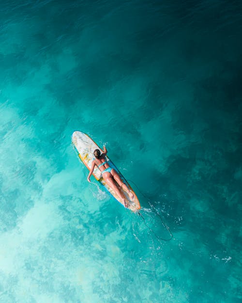 Woman in Blue Bikini Surfboarding on Sea