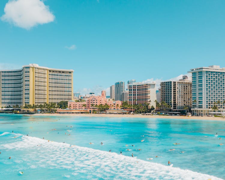 Surfers And Buildings At The Waikiki Beach