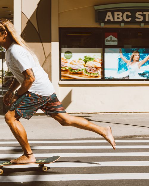 Free Man skateboarding quickly across a zebra crossing in a city area. Stock Photo