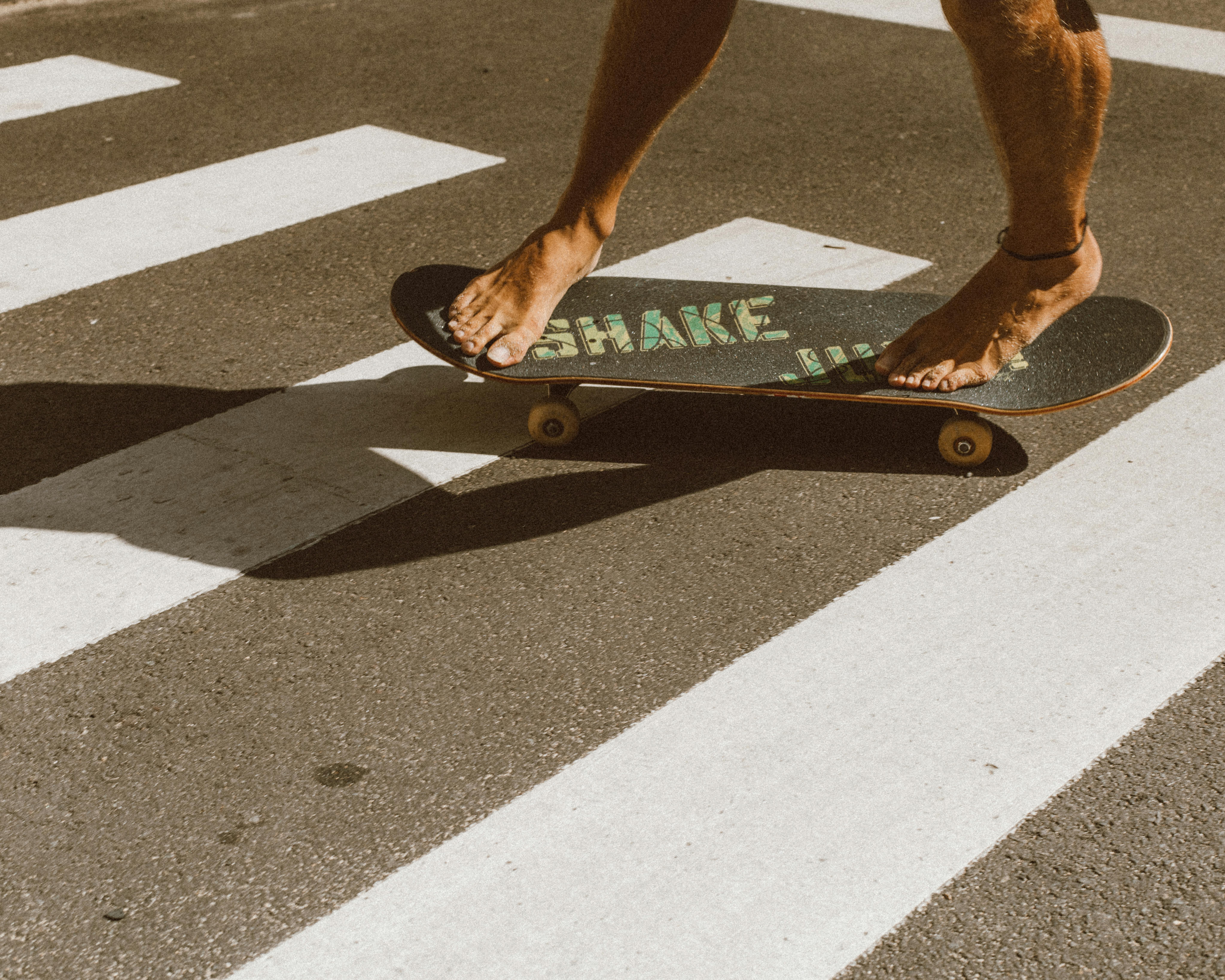 阳光明媚的日子里，赤脚滑板者穿过马路