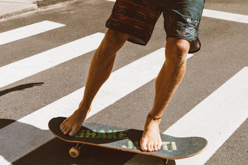 A Person Wearing Shorts Riding a Skateboard Barefoot