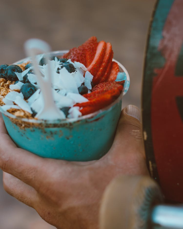 A Person Holding A Cup Of Ice Scramble With Fruits Toppings