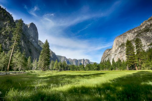 Free Experience the breathtaking beauty of Yosemite Valley with its lush fields and towering cliffs under a blue sky. Stock Photo