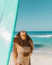 一位穿着豹纹泳衣的快乐女人在海边拿着冲浪板享受阳光明媚的一天