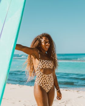 一名身着豹纹泳衣的非洲裔美国女人，在阳光明媚的海滩上拿着冲浪板
