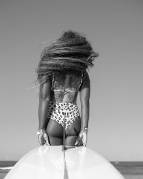 一名头发蓬乱、身穿黑白相间豹纹泳衣的女子手持冲浪板