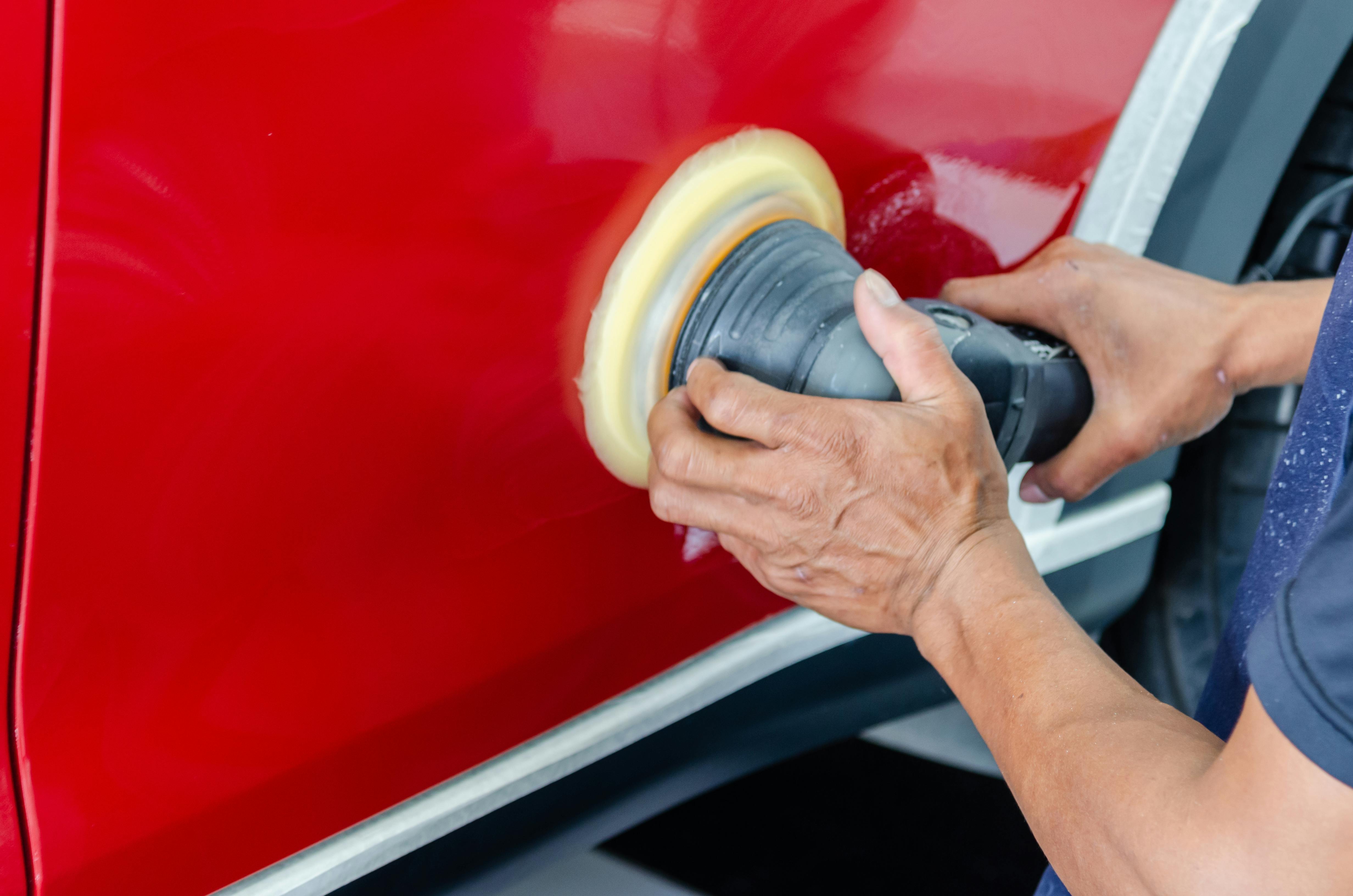 Person applying paint protection film to a car, representing car detailing services.