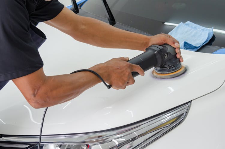 A Person Polishing The White Car