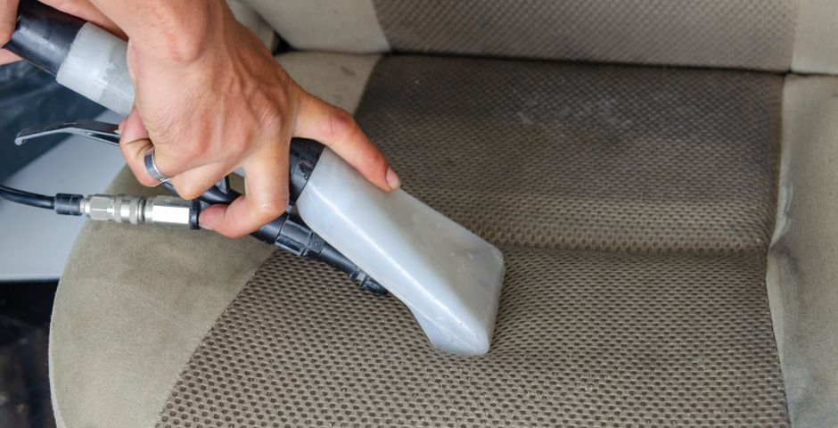 Vacuuming a fabric car seat — cleaning out crumbs and egg cases is the first step before baiting