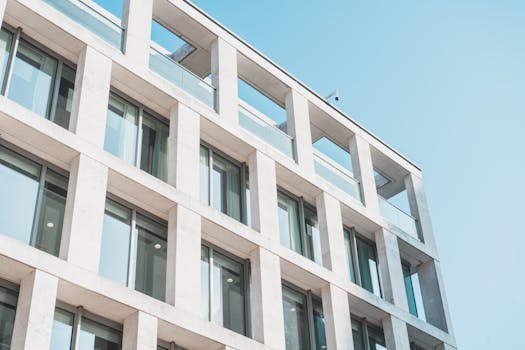 Contemporary office building with glass and concrete design, viewed from a low angle against the sky.