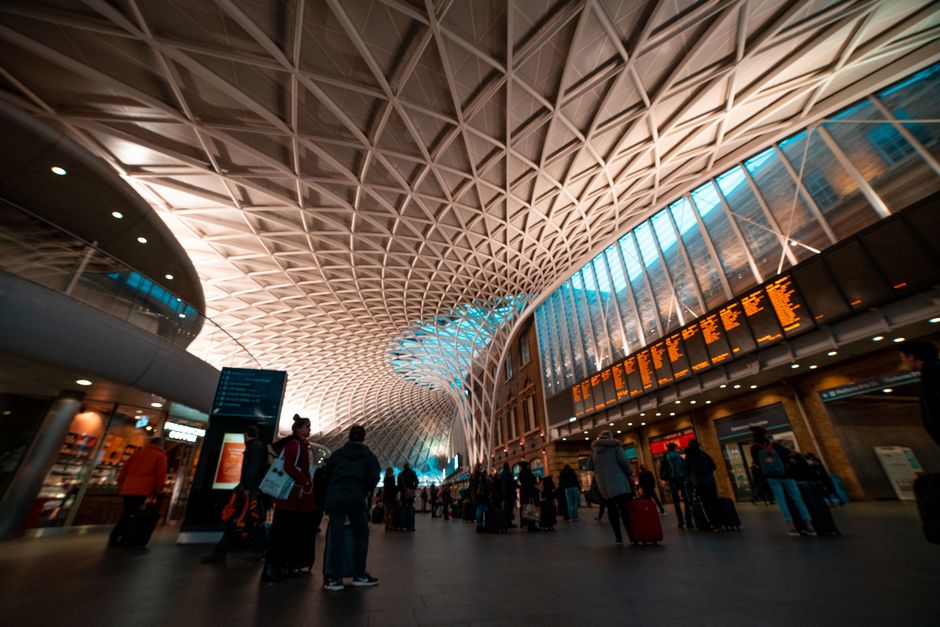Busy scene inside King's Cross Station with travelers and luggage under iconic roof.