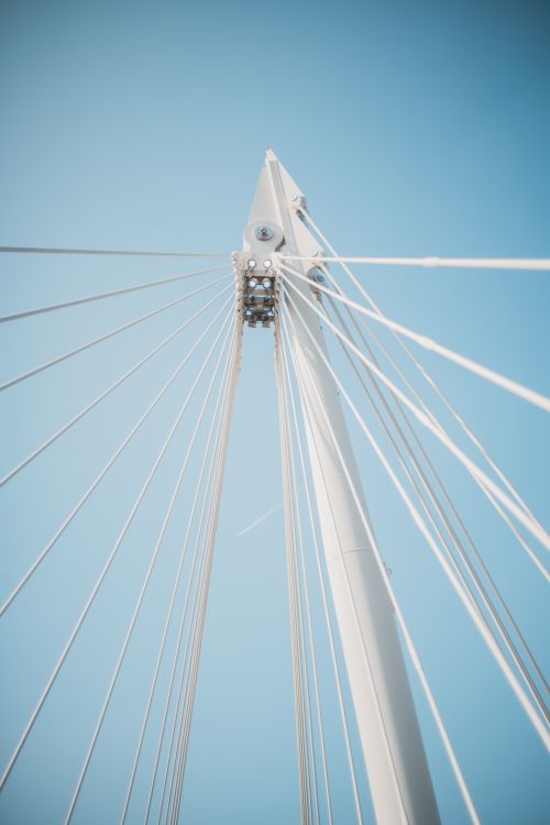 Free Close-up of a modern bridge's cables against a clear blue sky in London. Stock Photo