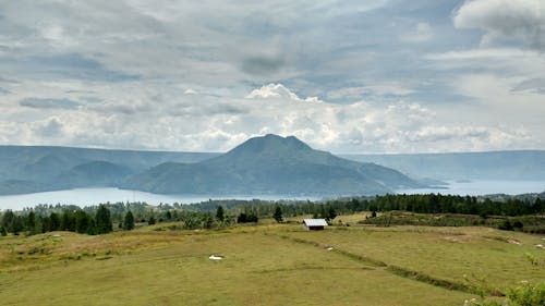 Green Grass Field Near a Mountain Under the White Clouds