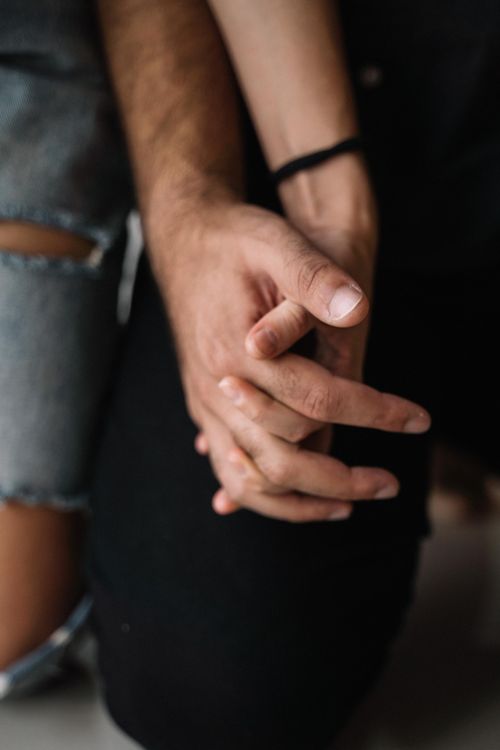 Free Close-up of a couple holding hands, symbolizing intimacy and affection. Stock Photo