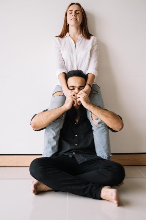 Free A joyful couple sitting indoors with the woman on the man's shoulders, enjoying a playful moment. Stock Photo