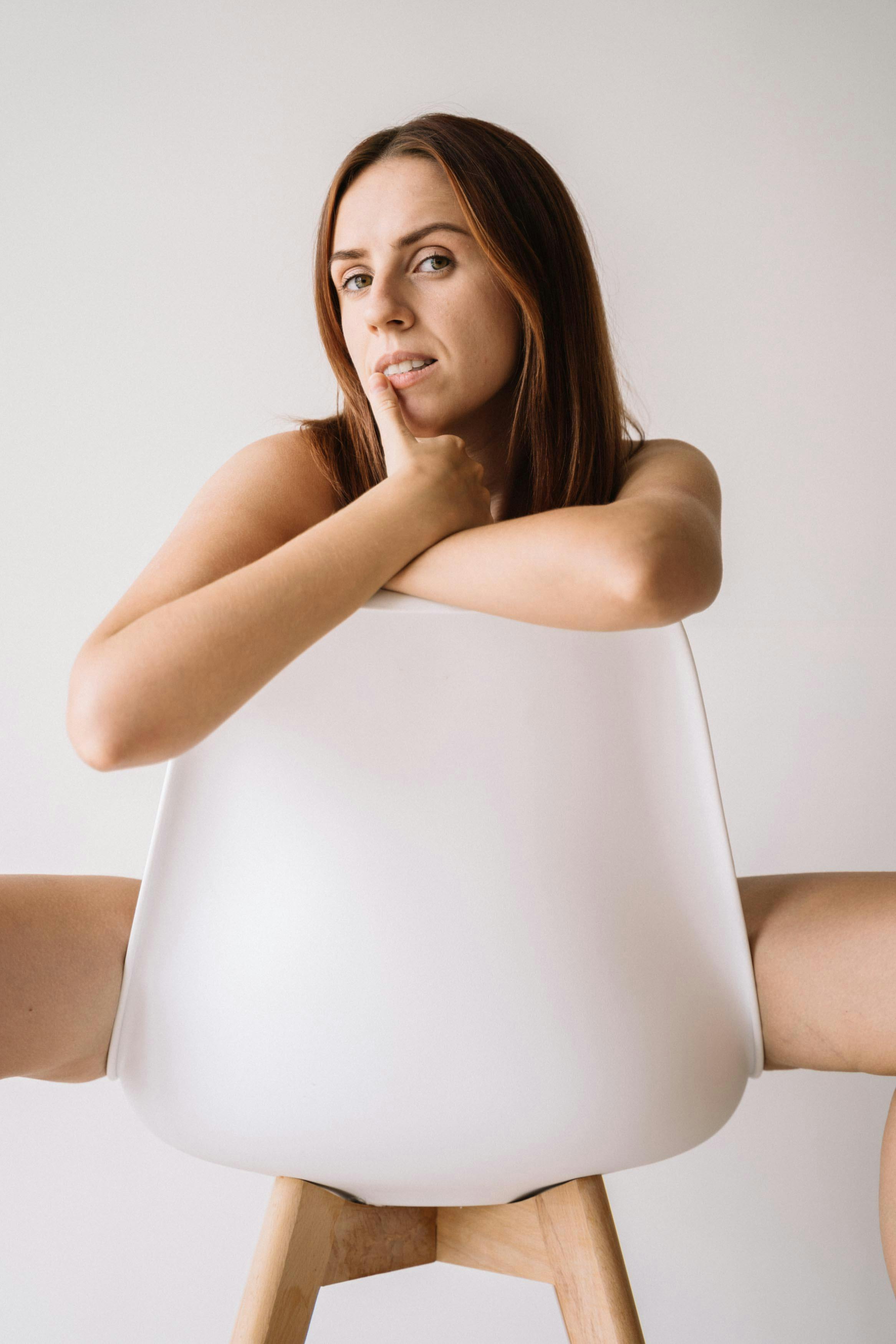 一位坐在室内现代椅子上的女性富有创意而时尚的肖像，背景为中性