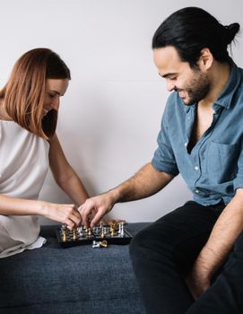 一对年轻夫妇在室内愉快地下棋，享受休闲时光