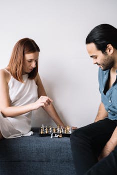 一对夫妇坐在沙发上，全神贯注地下着国际象棋，象征着联系与策略