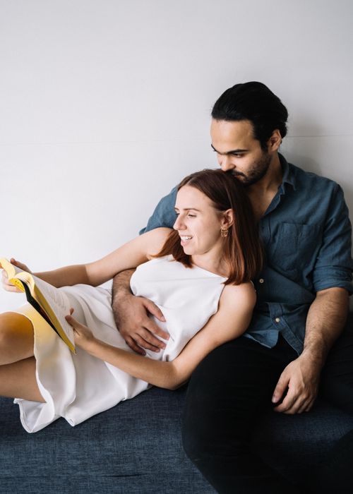 Free A happy couple relaxes indoors together, enjoying a book in a cozy setting. Stock Photo