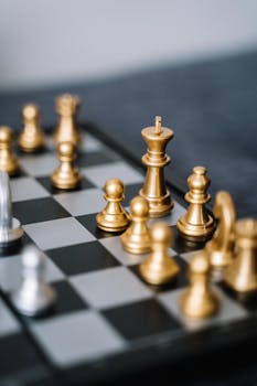Close-up of golden chess pieces on a chessboard, ready for a strategic move.