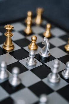 Macro shot of a chessboard featuring gold and silver pieces in strategic play.