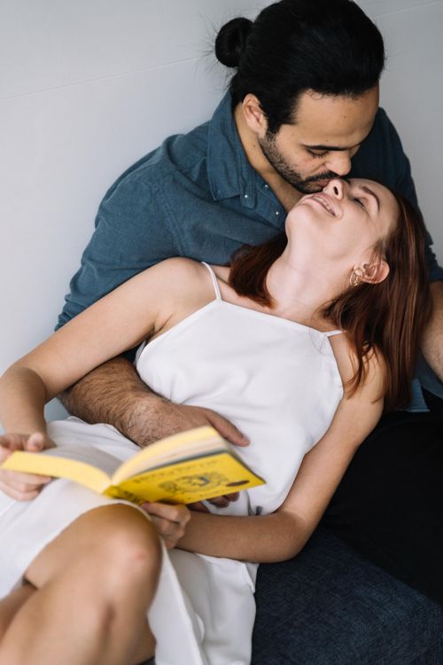 Free A loving couple sharing a tender moment while reading a book together indoors. Stock Photo