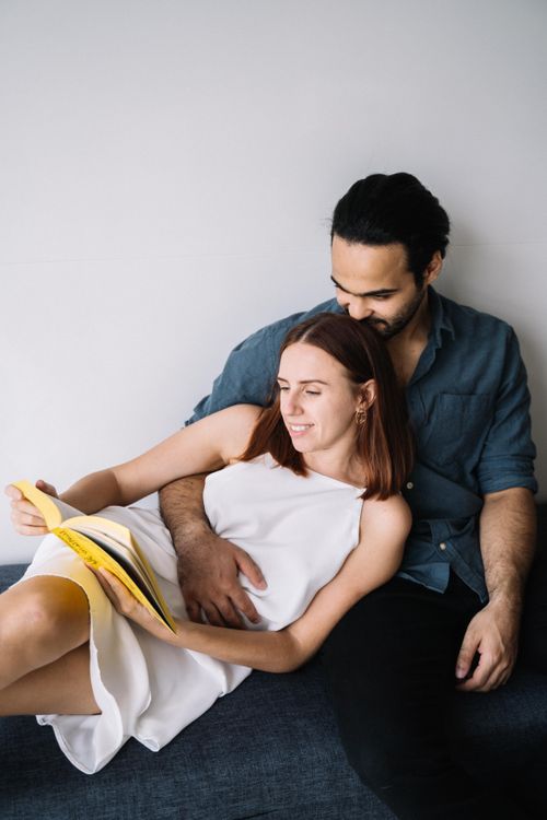 Free Happy couple sharing a peaceful moment reading a book together on the couch. Stock Photo