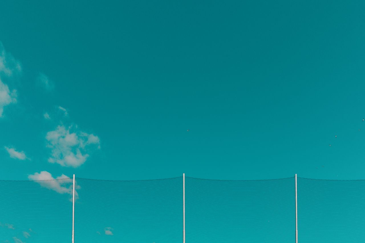 minimalist outdoor scene with a teal sky gentle clouds and netting ide