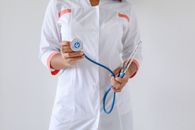 特写镜头中，一位女医生手持蓝色听诊器，凸显了医疗保健与专业精神
