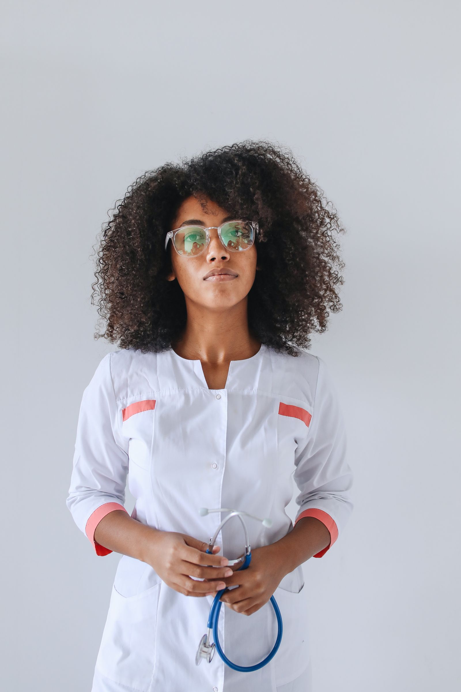 A Black female physician in a white coat holds a stethoscope, representing the neurologists who diagnose and treat multiple sclerosis in Black patients.