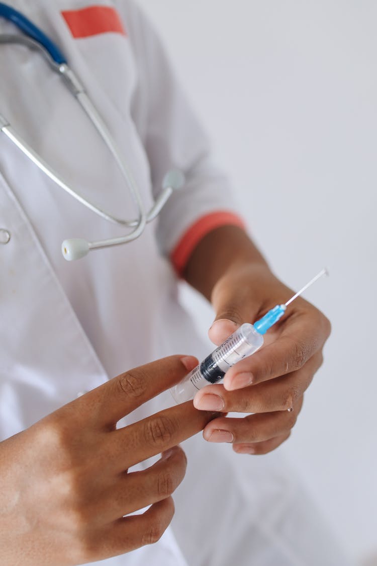 Hands Holding A Syringe Filled With Liquid