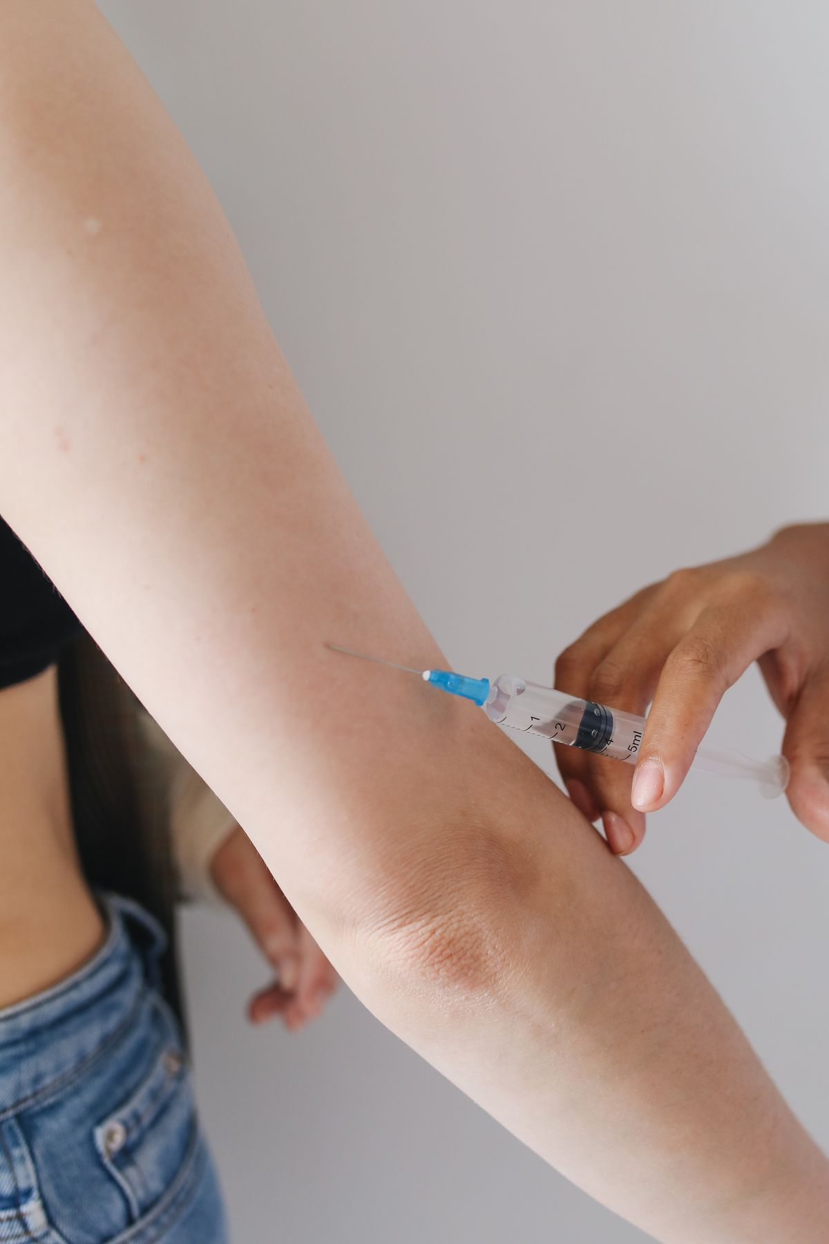 A gloved hand administering an injection into a patient’s arm in a clinical setting, representing physician-supervised glutathione injections offered in Virginia Beach
