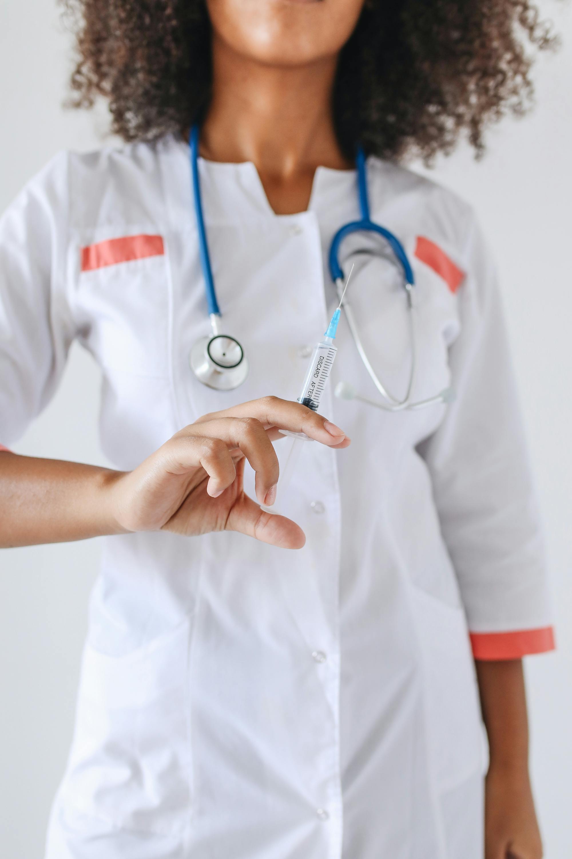 一位女医生穿着白大褂，手里拿着注射器和听诊器