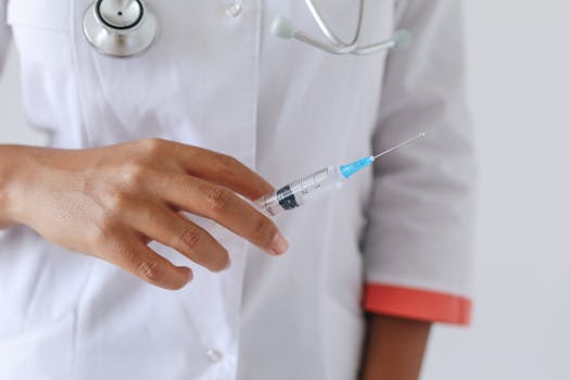 Close-up of a healthcare professional holding a syringe, ready for injection. Focus on hand and syringe.