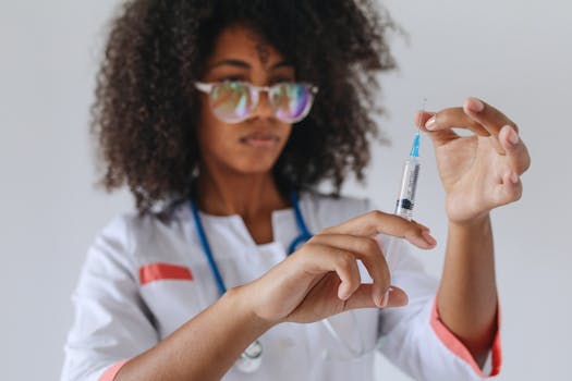 A focused healthcare professional with curly hair preparing a syringe for medical use.