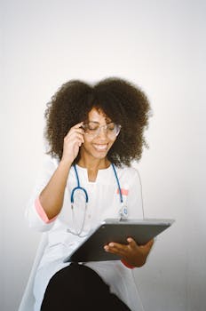 一位非洲裔美国女医生在使用平板电脑时微笑，展现了现代医疗保健的场景