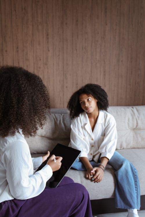 Free Two women engaged in a therapy session on a couch, highlighting mental health support. Stock Photo