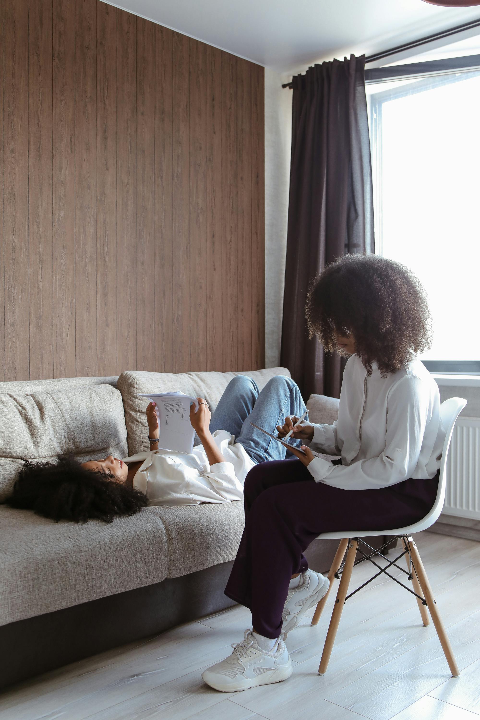 一位治疗师在咨询期间坐在沙发上为一位成年患者做笔记