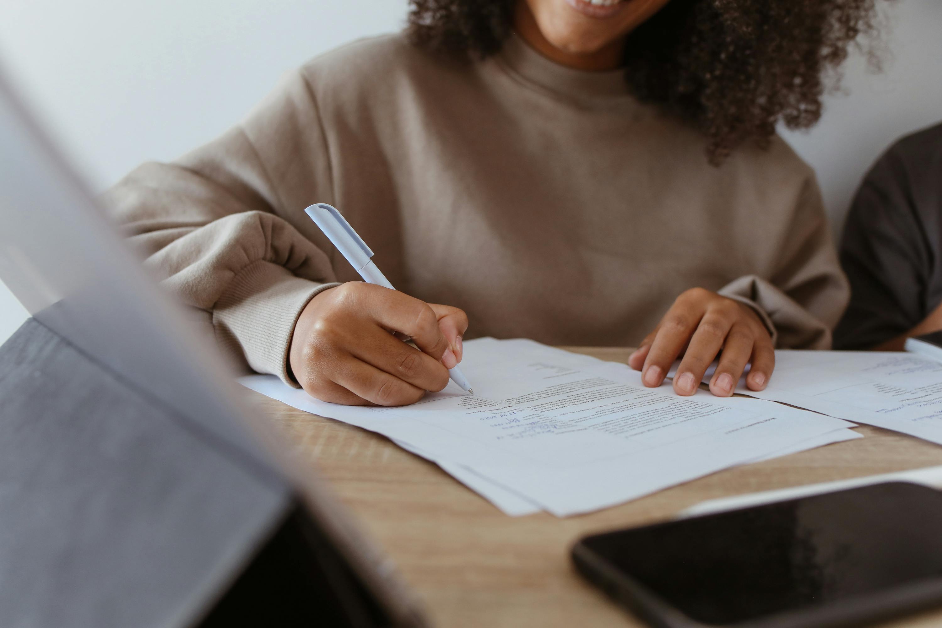 Woman signing important custody modification paperwork with attorney assistance.